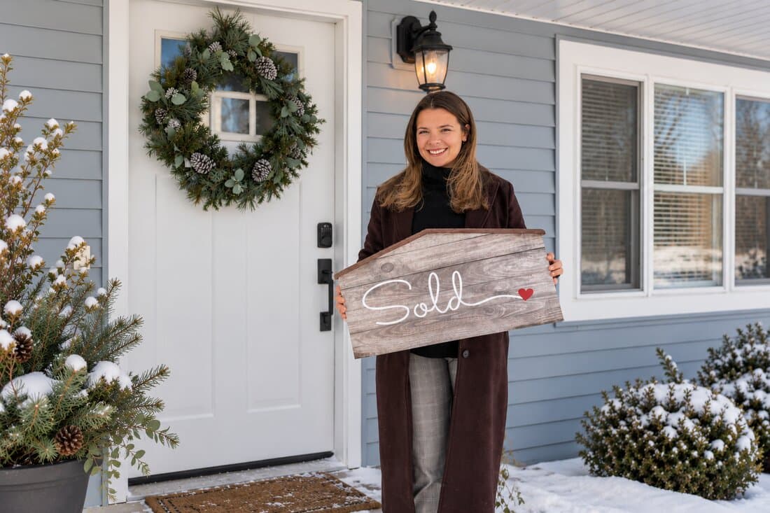 Ashten Tucker, First Keys founder, holding a 'Sold' sign outside a home